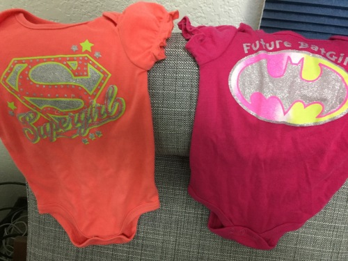 Supergirl and Batgirl onesies